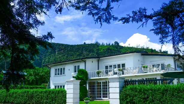 A two-story white building with a balcony, surrounded by greenery and a mountainous backdrop. - Country House - Nuwara Eliya (Nuwara Eliya)