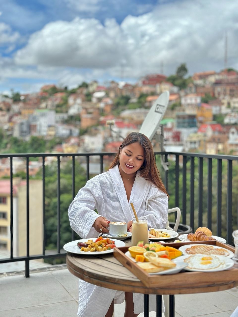 Una persona cenando en un balcón con vista a la ciudad.