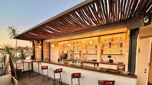 Uma área de bar com teto de madeira, paredes de tijolo branco e vista para a cidade.