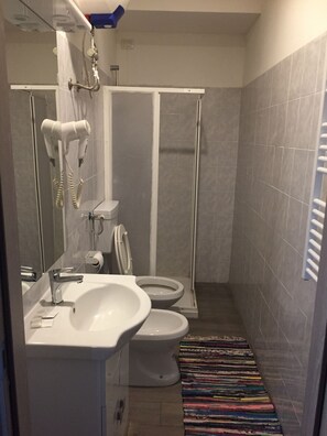 A bathroom with a sink, two toilets, a shower, and a hairdryer. - Hotel Antonelli (Milan)