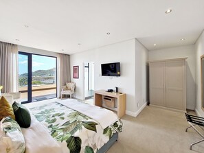Una habitación de hotel moderna con una cama grande, un televisor, un escritorio y un armario.