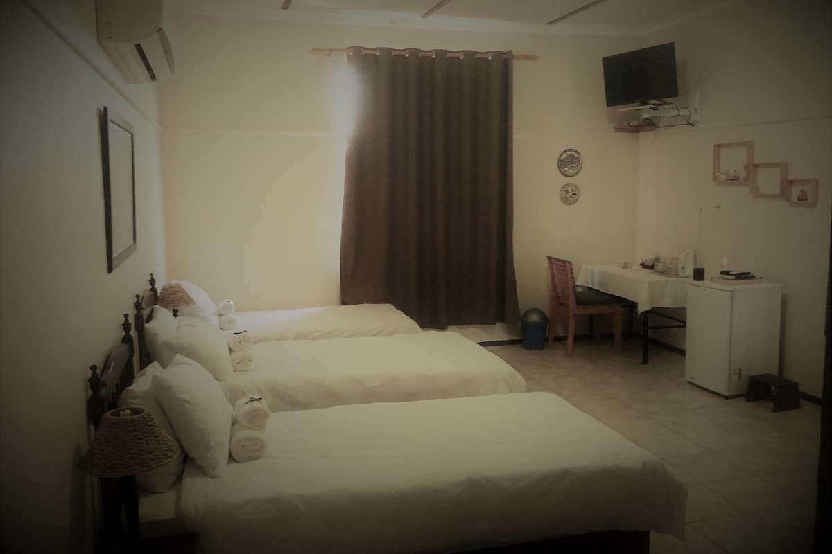 Habitación de hotel con dos camas, un escritorio, una silla, un televisor y una mesita.