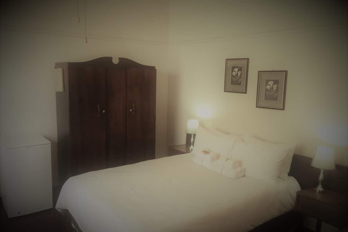 Un dormitorio con cama, armario y dos lámparas de pared.