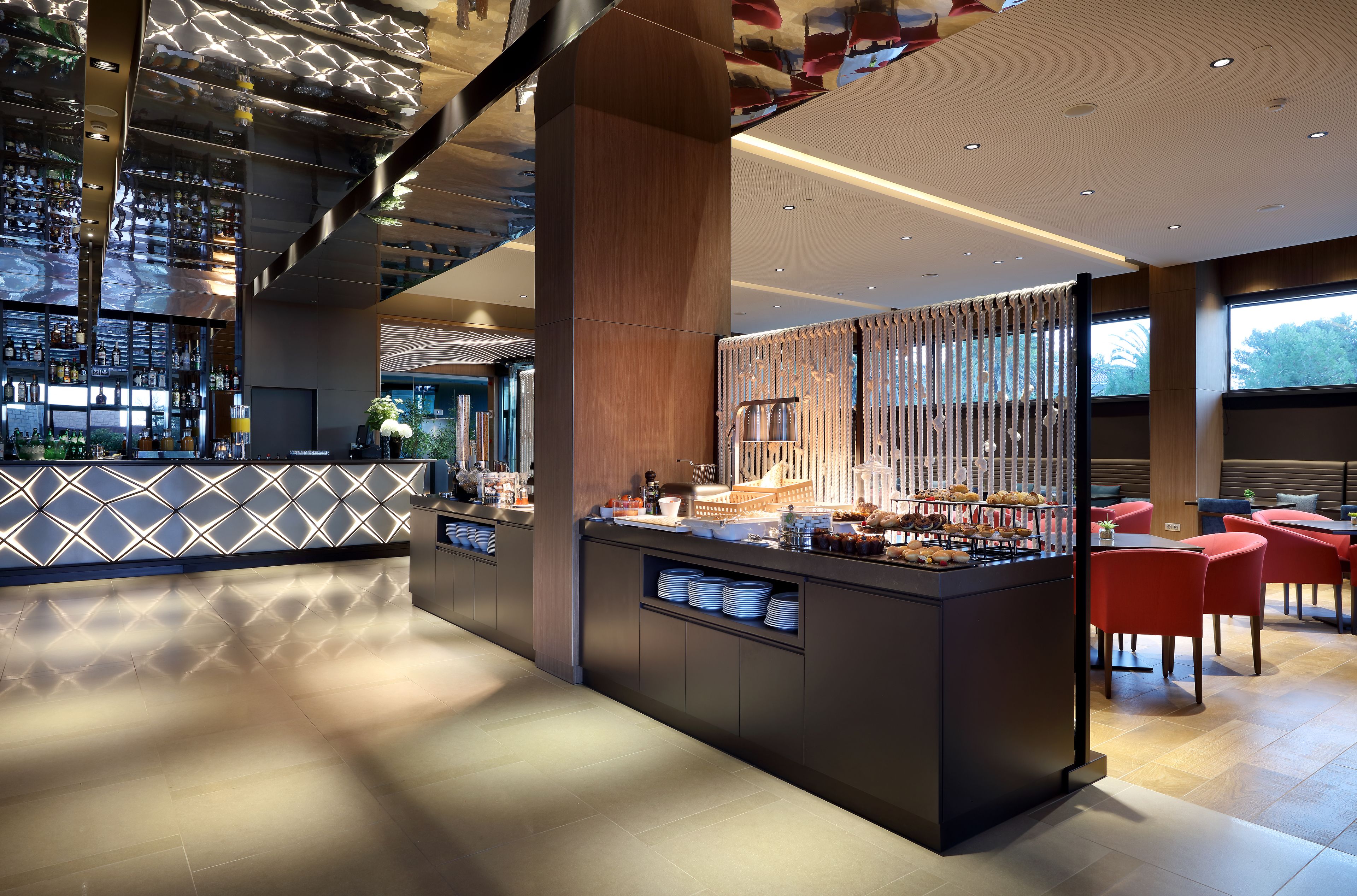 A modern hotel lobby with a bar area, seating, and a decorative wall.