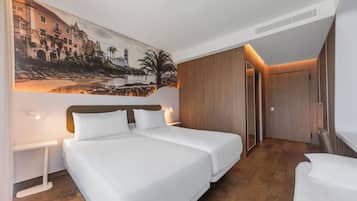 Moderni hotellihuone, jossa on suuri sänky, yöpöytä, seinälle ripustettu taulu ja puinen vaatekaappi.