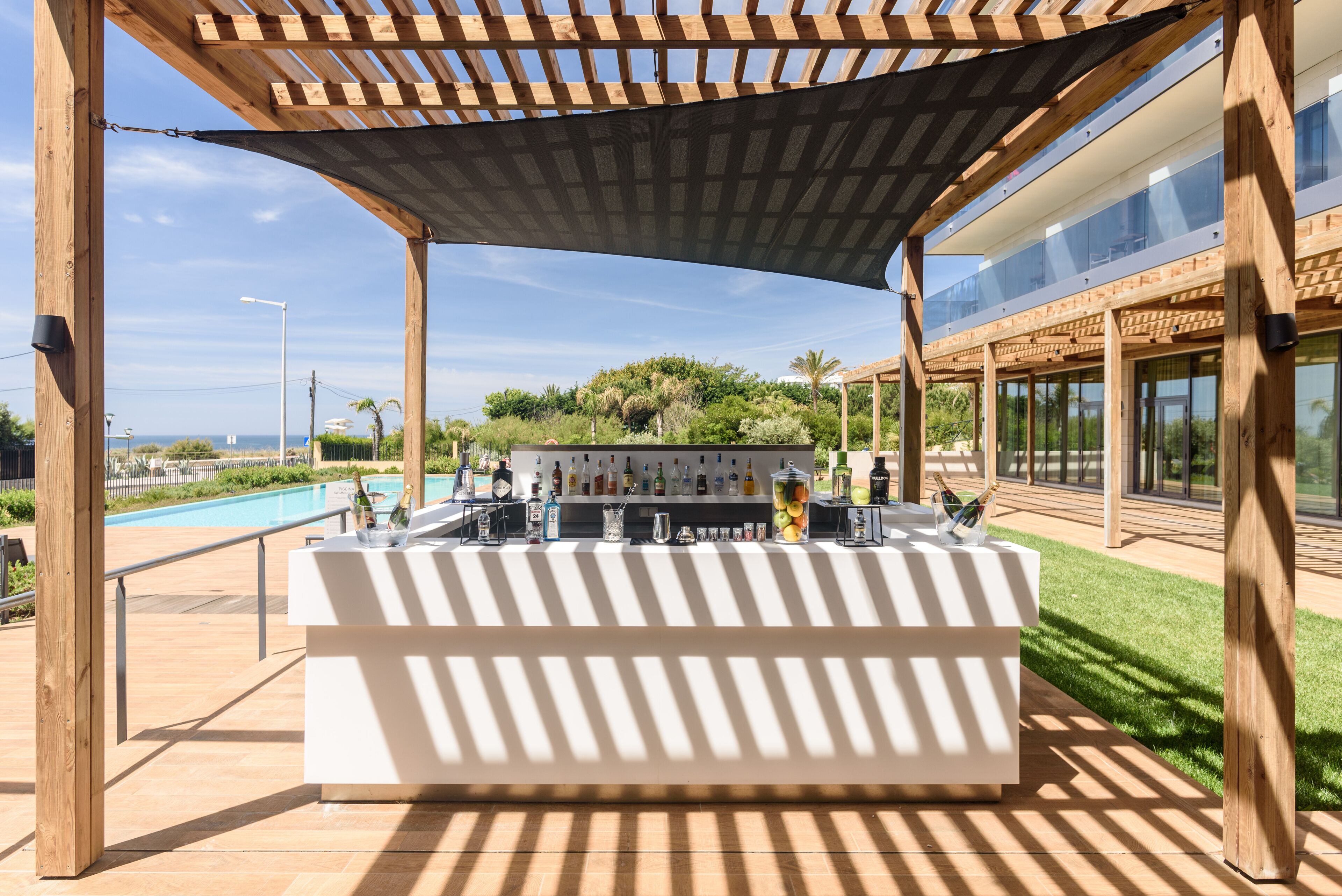 A covered outdoor bar area with a pool in the background.