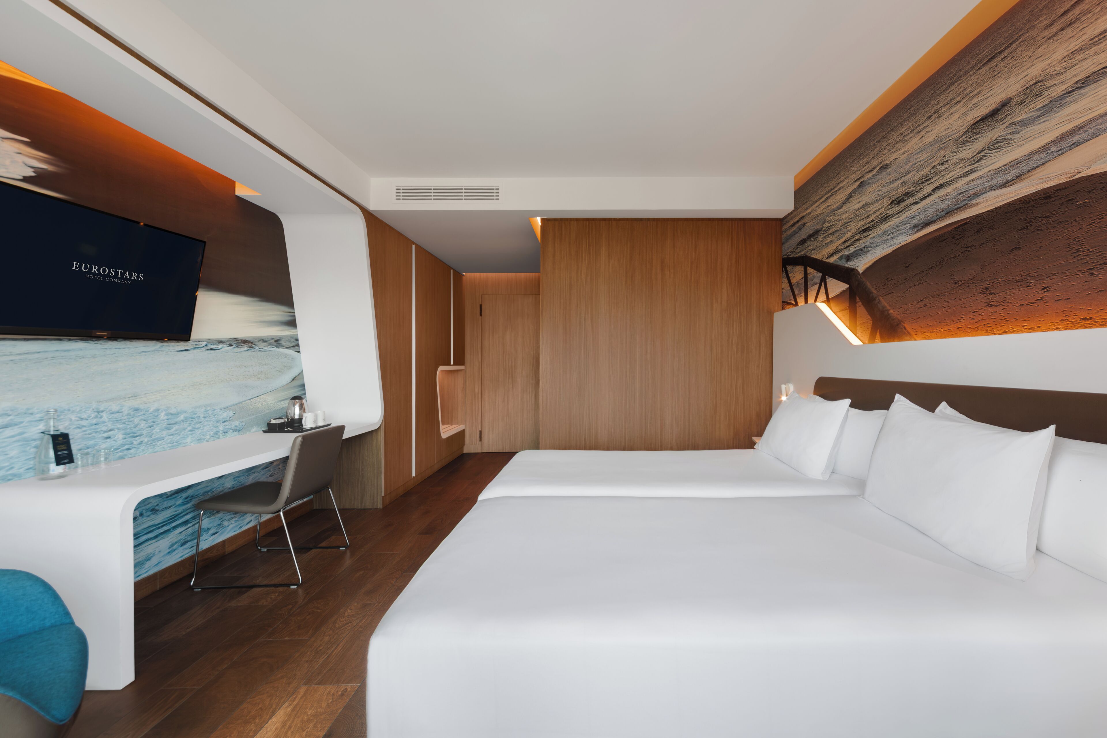 A modern hotel room with a large bed, a desk, and a television.