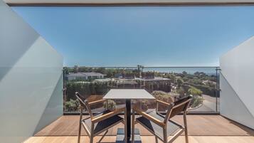 Un balcón con mesa y sillas, con vistas a una zona residencial con casas y vegetación.