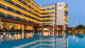 Un hotel con piscina, varios balcones y una fachada bien iluminada.