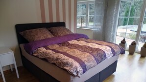 A bed with a patterned bedspread, a nightstand, and a window with a view of the outdoors. - Hannover Guest House (Hannover)