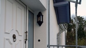 A white door with a lion head knocker, a small black lantern, and a metal railing on a balcony. - Hannover Guest House (Hannover)
