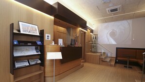 Een moderne receptie met houten lambrisering, een receptiebalie, een trap en een zithoek.