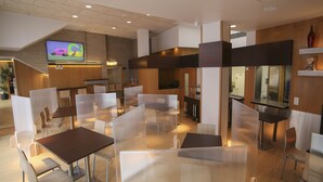 Een modern restaurant met hoge tafels en stoelen, een aan de muur bevestigde televisie, en houten details.