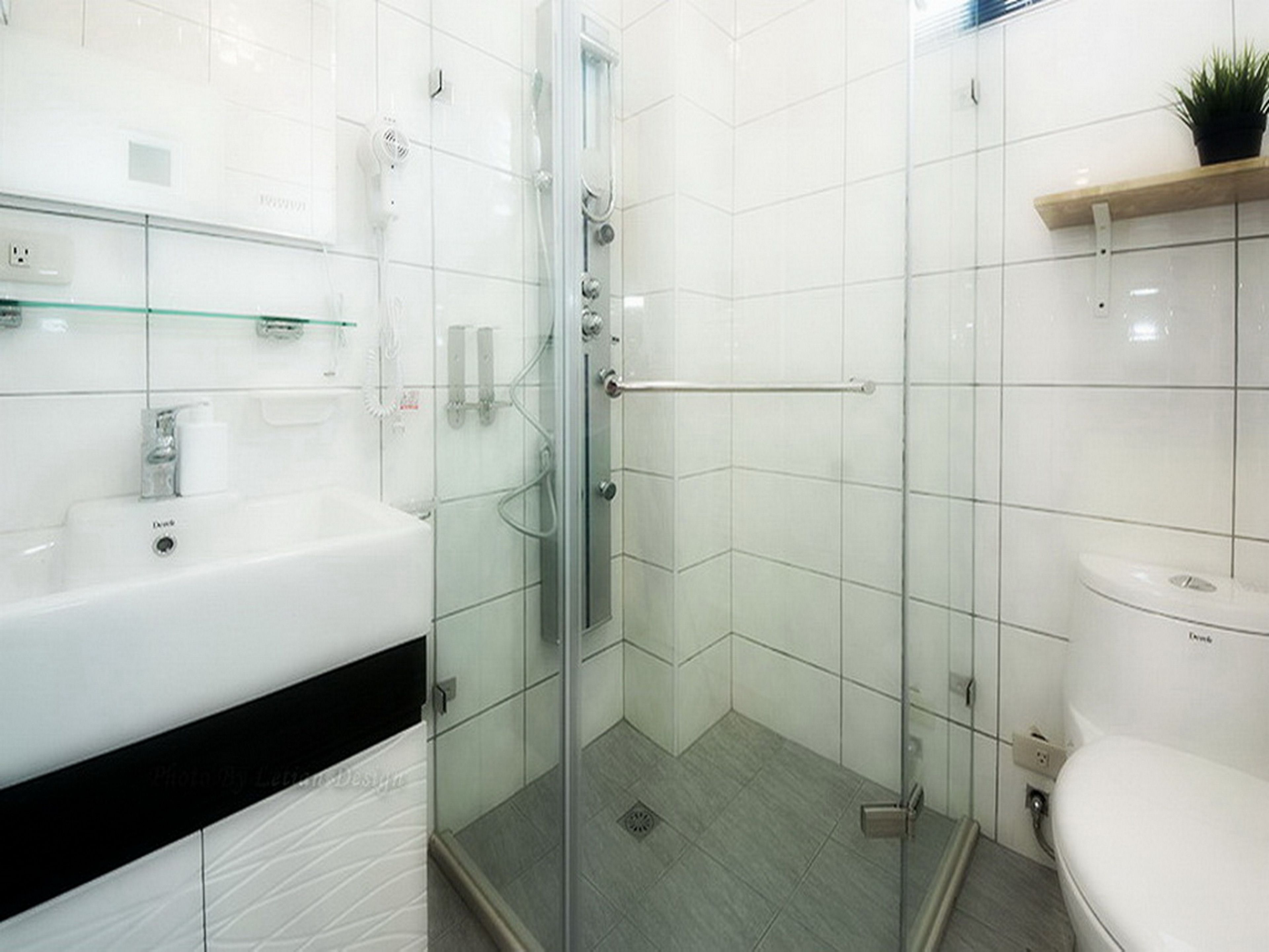 A modern bathroom with a glass shower enclosure, a white sink, and a toilet.