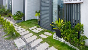 Un bâtiment moderne avec une enseigne en bois, un chemin pavé de pierres et des plantes en pot.