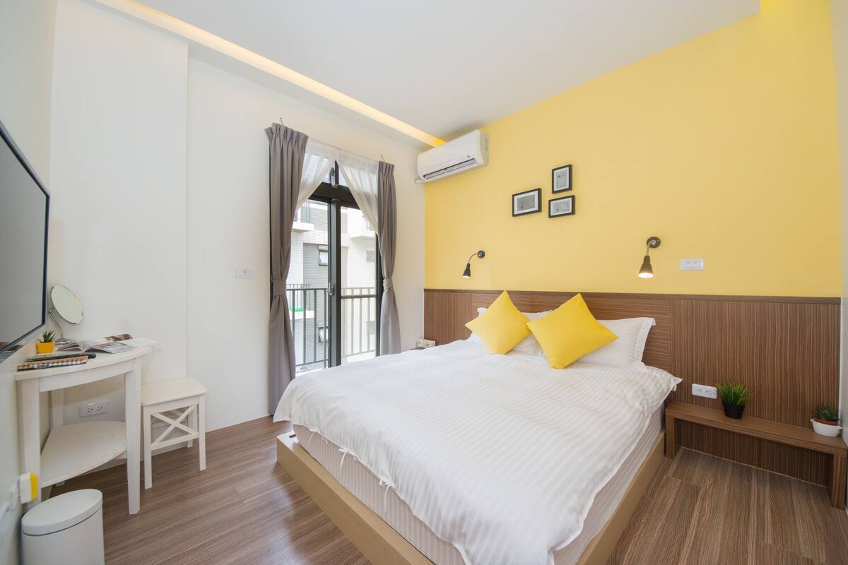 A hotel room with a large bed, a desk, and a small table.