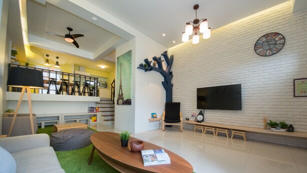 Un salon moderne avec un téléviseur à écran plat, une table basse en bois, un canapé et un tapis vert.