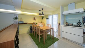 Une cuisine moderne avec un coin repas, comprenant une table en bois, des chaises, un tapis vert et une cuisinière encastrée.