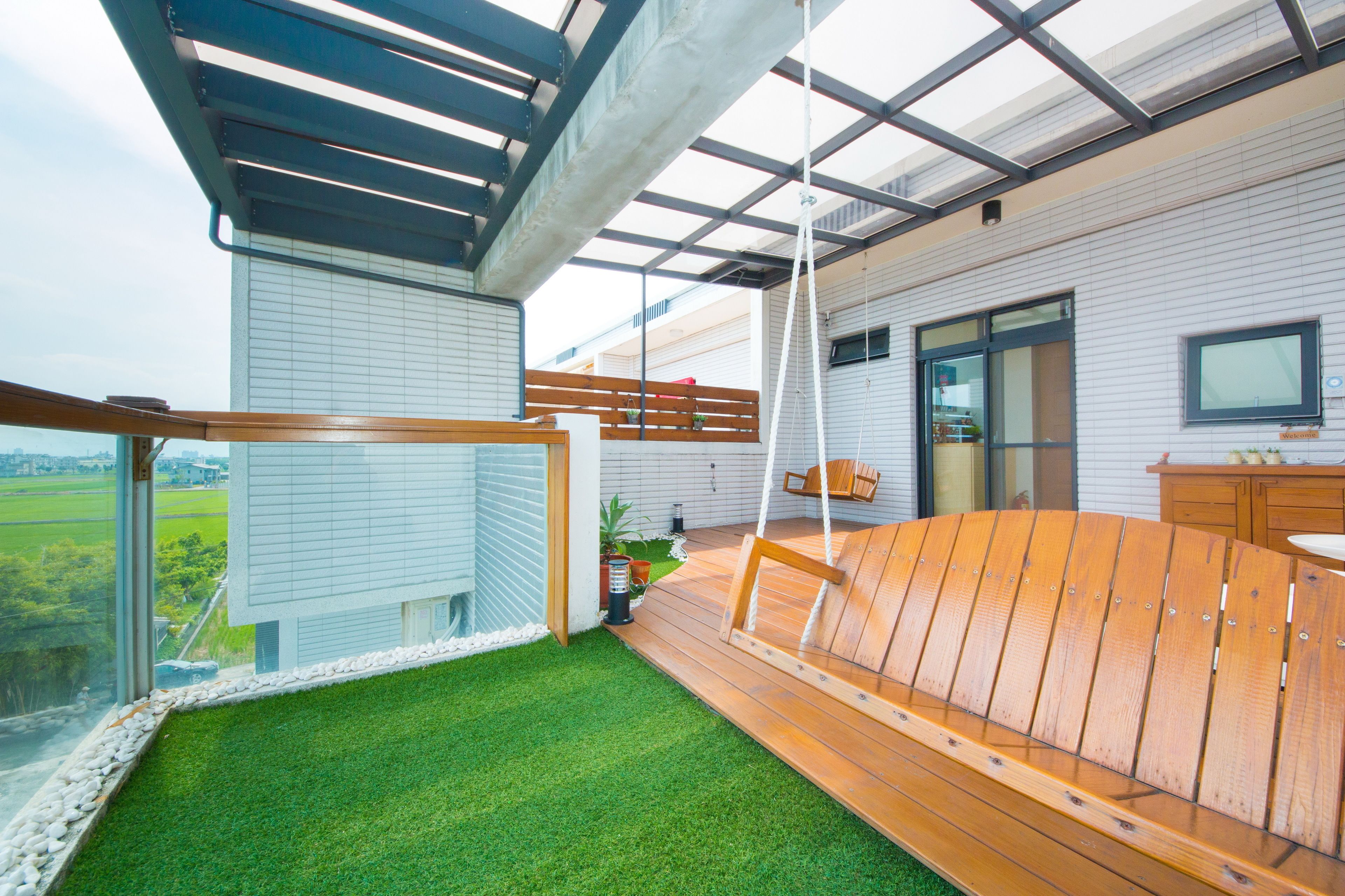 A balcony with artificial grass, wooden furniture, and a view of the countryside.