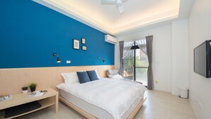 Une chambre d’hôtel moderne équipée d’un grand lit, d’un bureau, d’un ventilateur de plafond et d’une télévision.