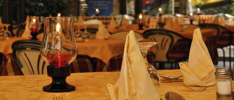 A dining table set with a candle, napkin, cutlery, and a salt shaker.