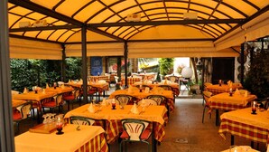 An outdoor restaurant with multiple tables covered by yellow umbrellas, arranged in rows.