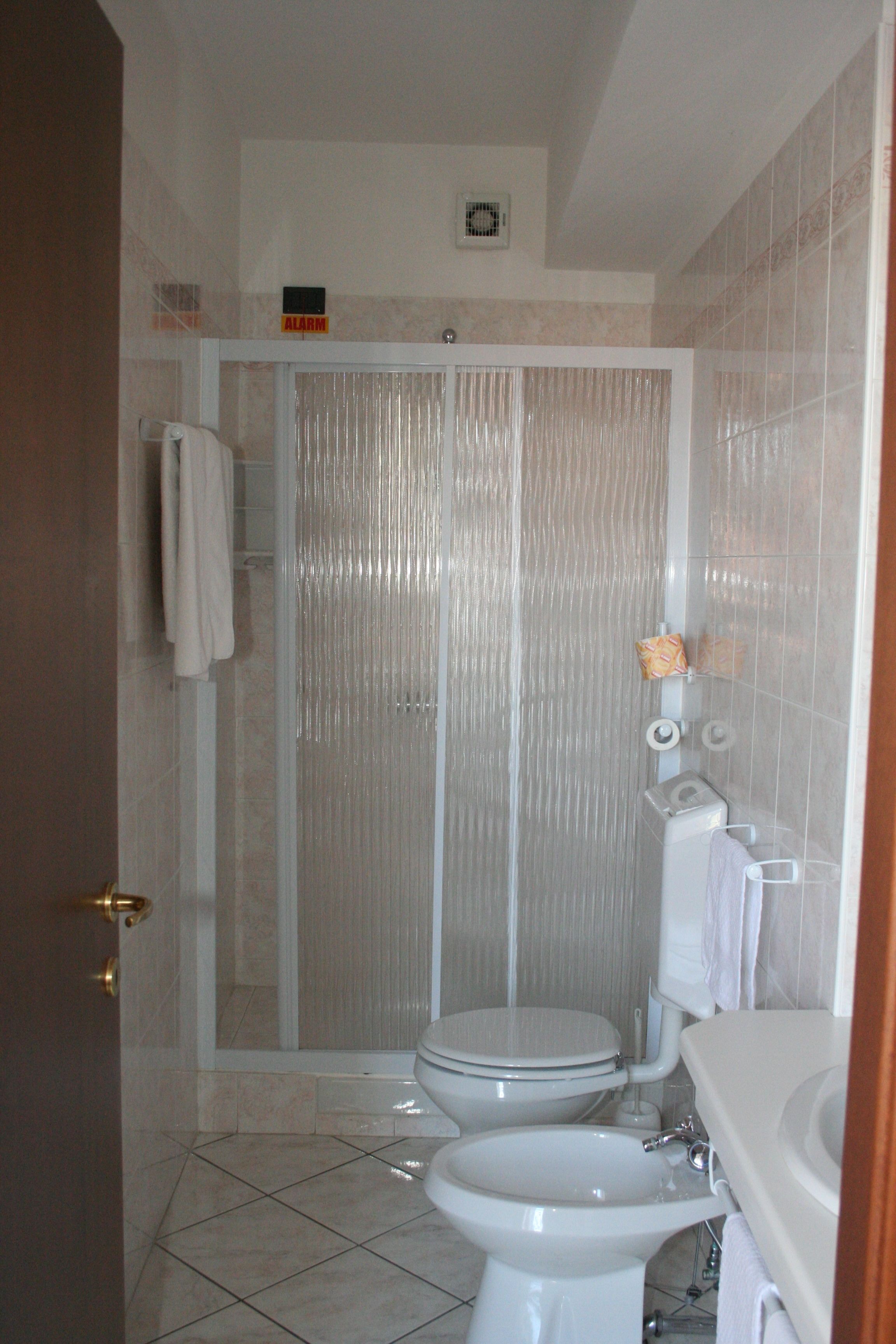 Een badkamer met douche, toilet en wastafel.