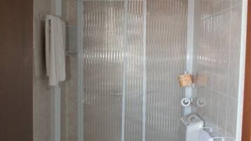 Een badkamer met douche, toilet en wastafel.