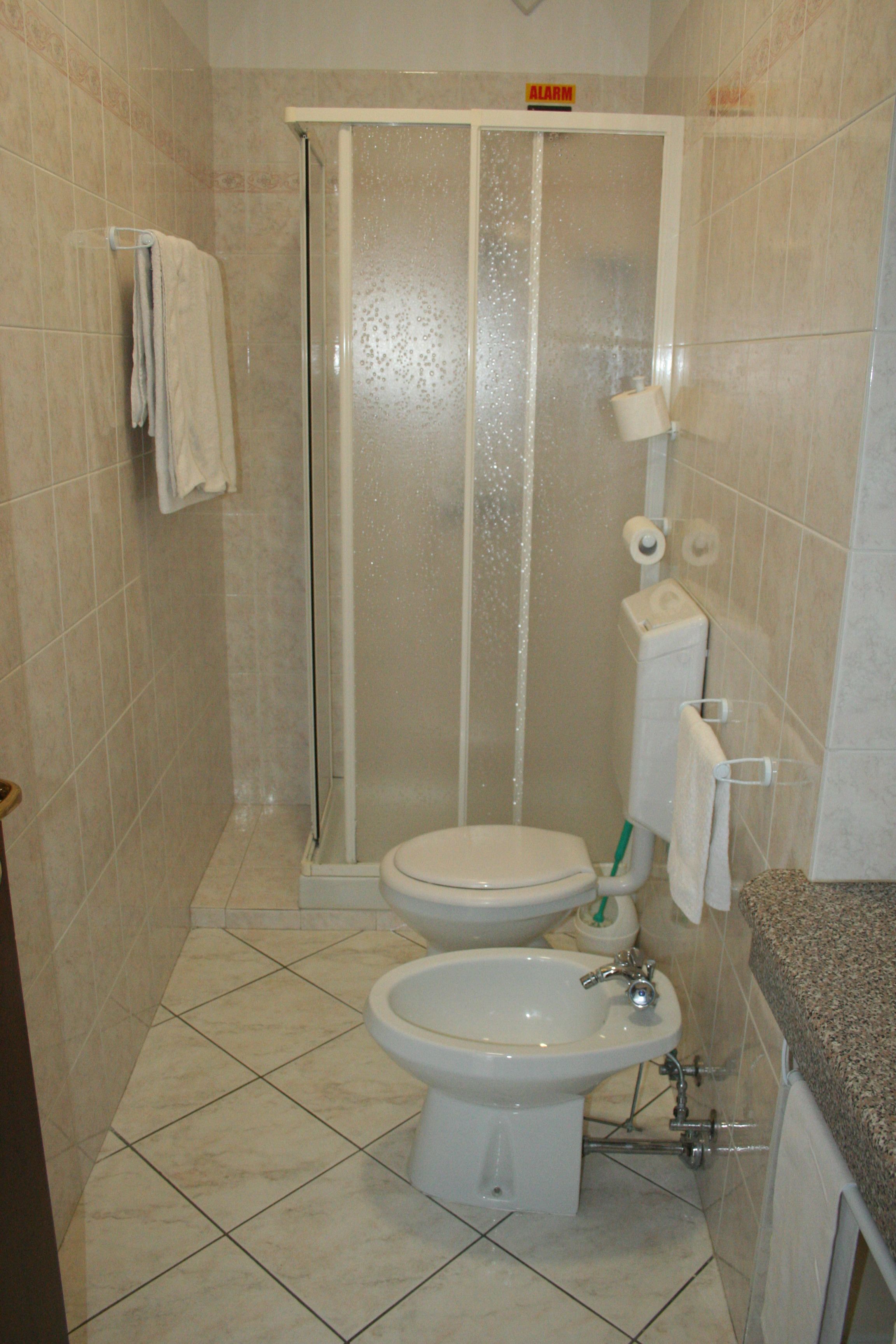 Un bany amb dutxa, vàter, bidet i paraigua de tovalloles.