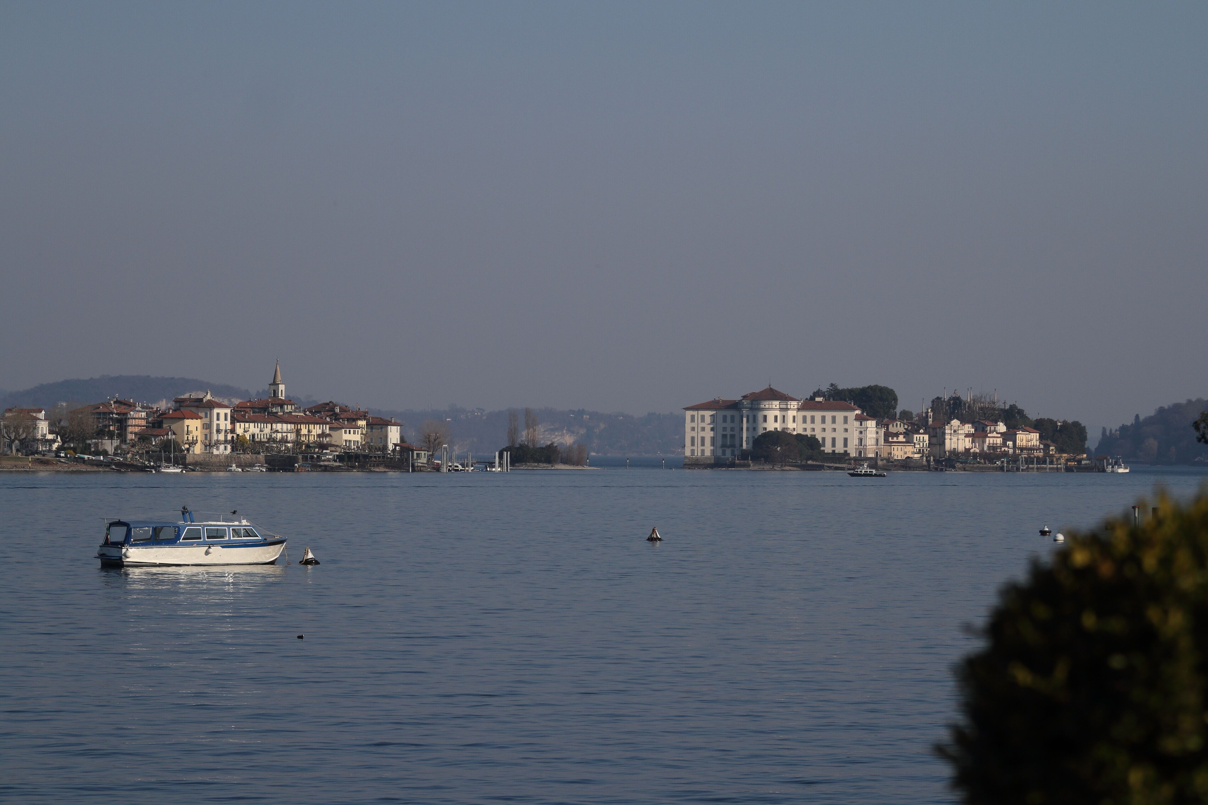A calm lake with a small boat and distant buildings along the shore.