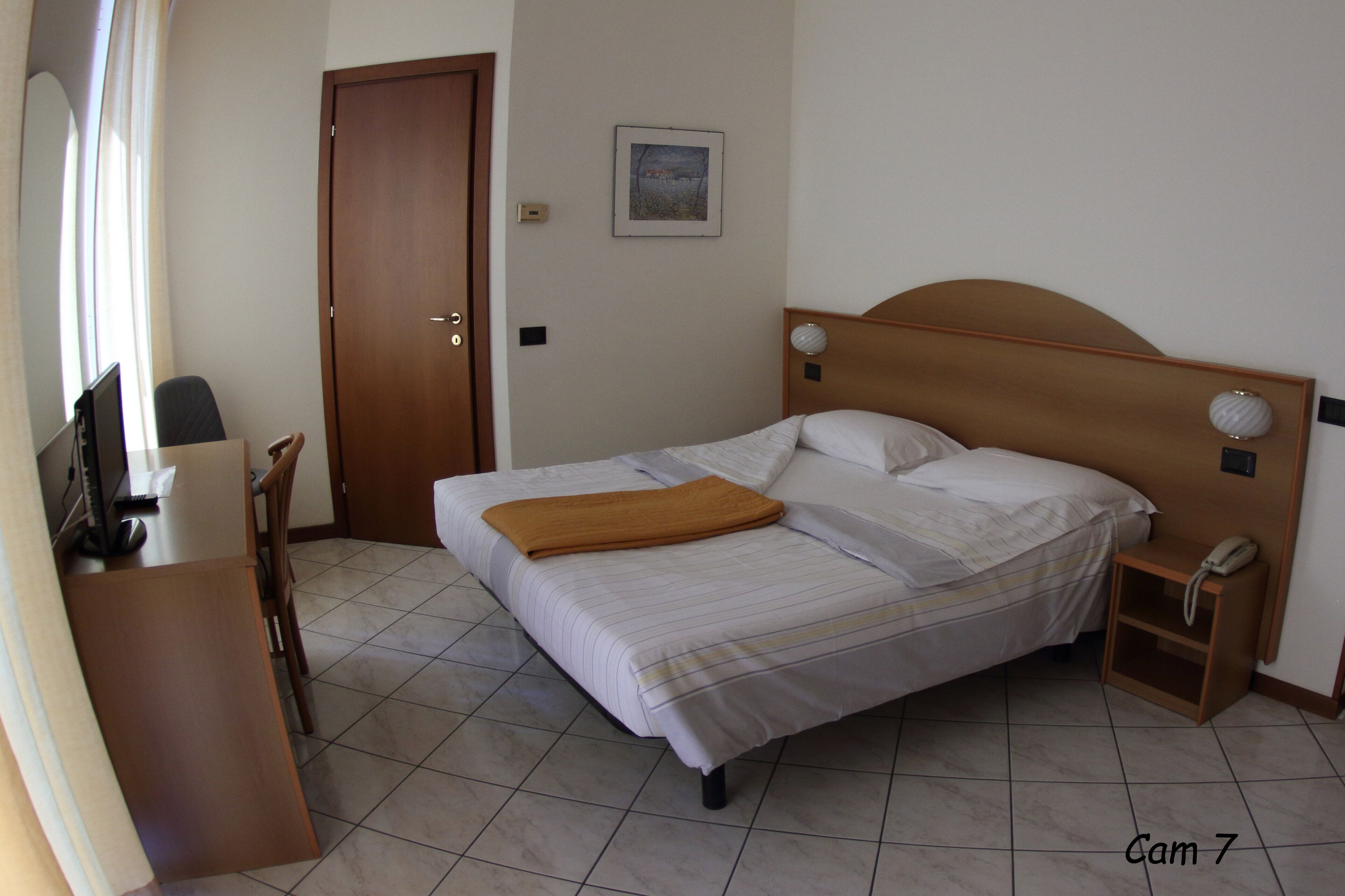 A neatly arranged bedroom with a bed, bedside table, and a desk with a chair.