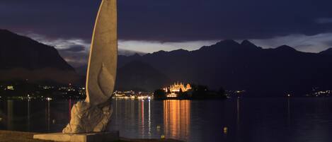 Une sculpture au bord du lac, de nuit, avec des montagnes en arrière-plan.