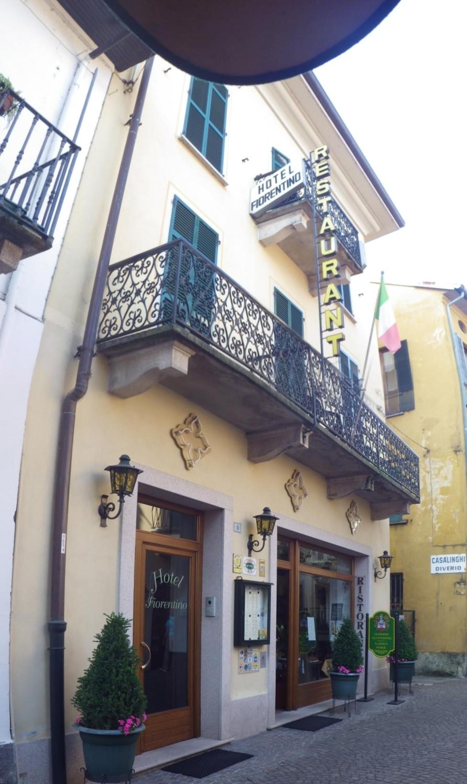 A hotel with a balcony, a sign reading "Hotel Fiorentino," and a flag.