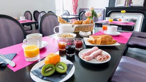 A breakfast setting with croissants, ham, kiwi, orange, and juice. - Hôtel Regina (Bordeaux)