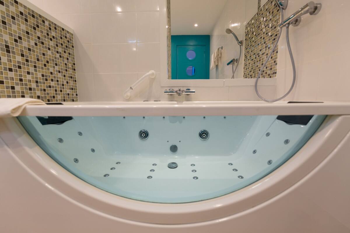 A modern bathroom with a freestanding bathtub, a shower area, and a tiled wall with a mosaic pattern.