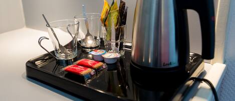 A tray with a coffee maker, glasses, cups, and condiments.