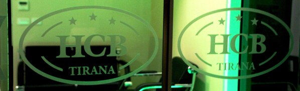 Dos logotipos circulares con el texto "HOB" y "TRANA" sobre una superficie de vidrio.