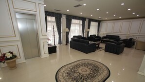 A spacious living room with a large, ornate rug, multiple sofas, and a flat-screen TV. - Capital Tirana Hotel (Tirana)