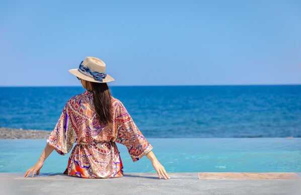 A person sitting by a pool with a view of the ocean. - Casa Di Mare (Santorini)