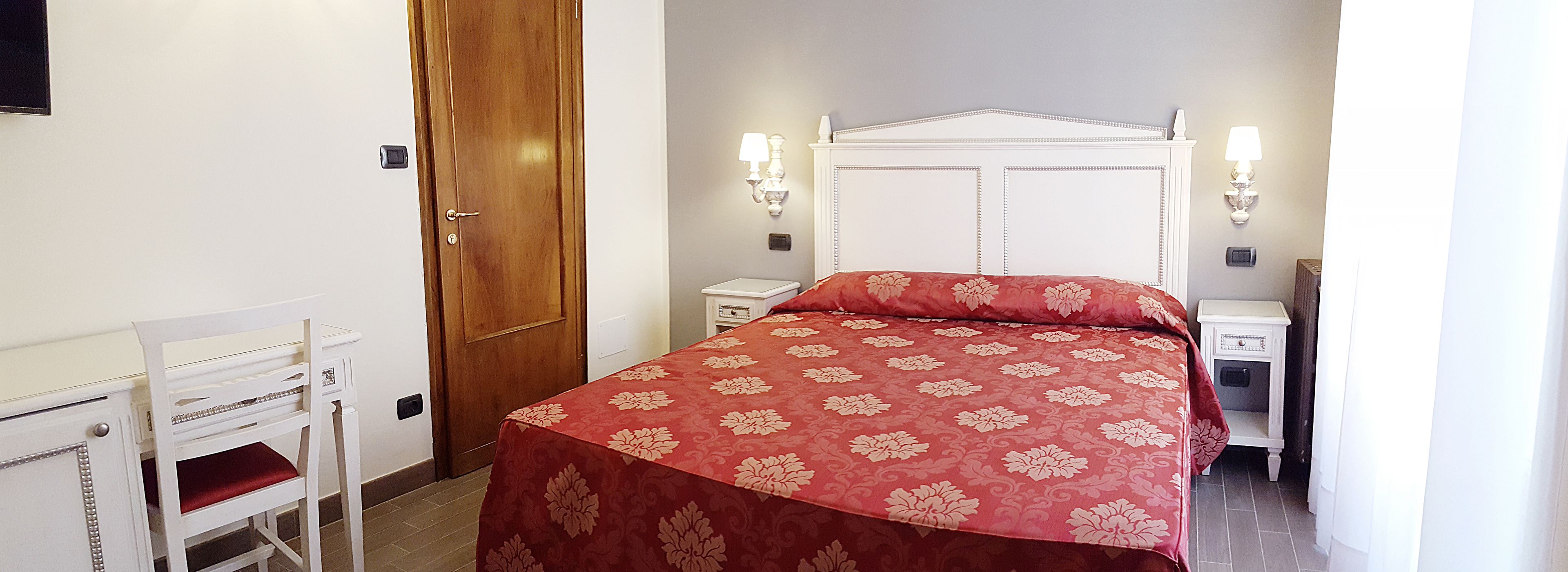 A bedroom with a bed, a nightstand, a desk, and a chair.