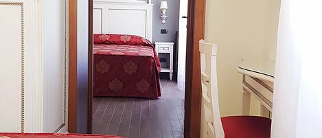 A hotel room with a bed, a desk, a chair, and a TV.