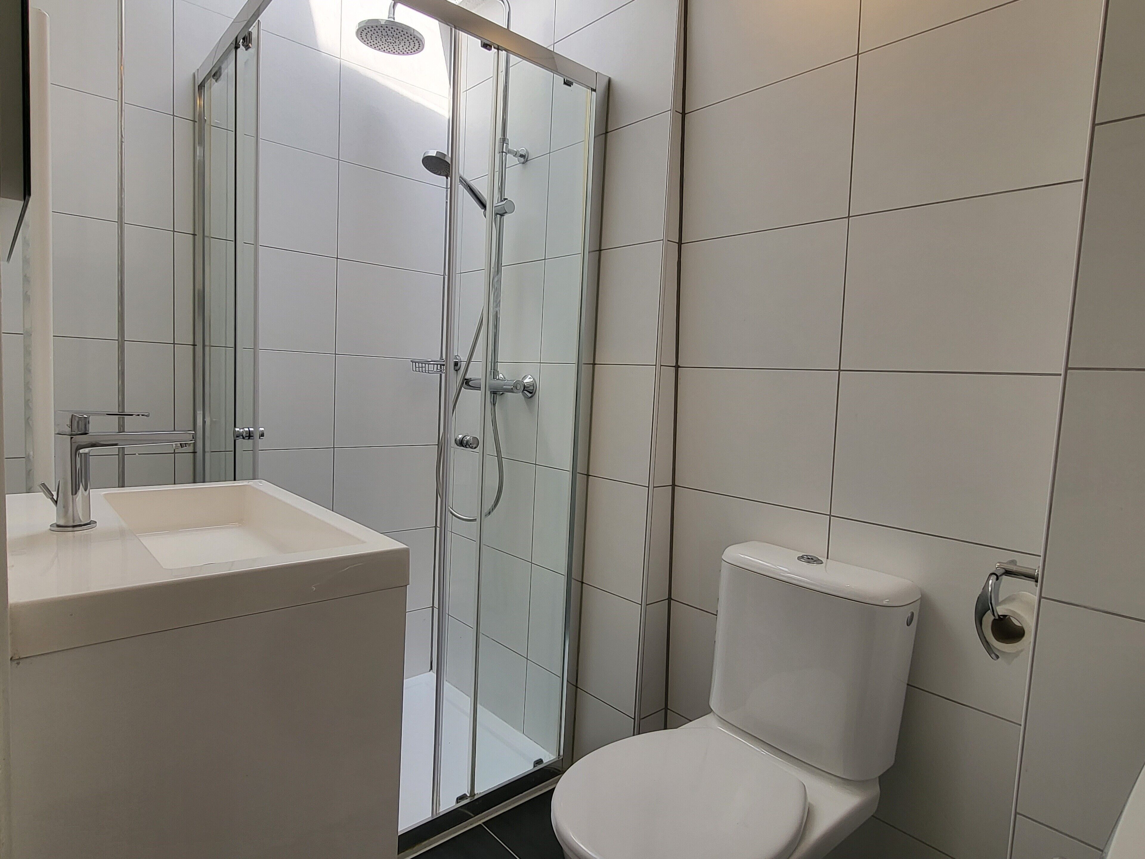 Une salle de bain avec une douche à parois de verre, un lavabo blanc et des toilettes.