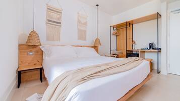Een moderne slaapkamer met een houten bed, een nachtkastje van hout, een bureau met stoel, een kledingkast en twee macramé decoraties aan de muur.