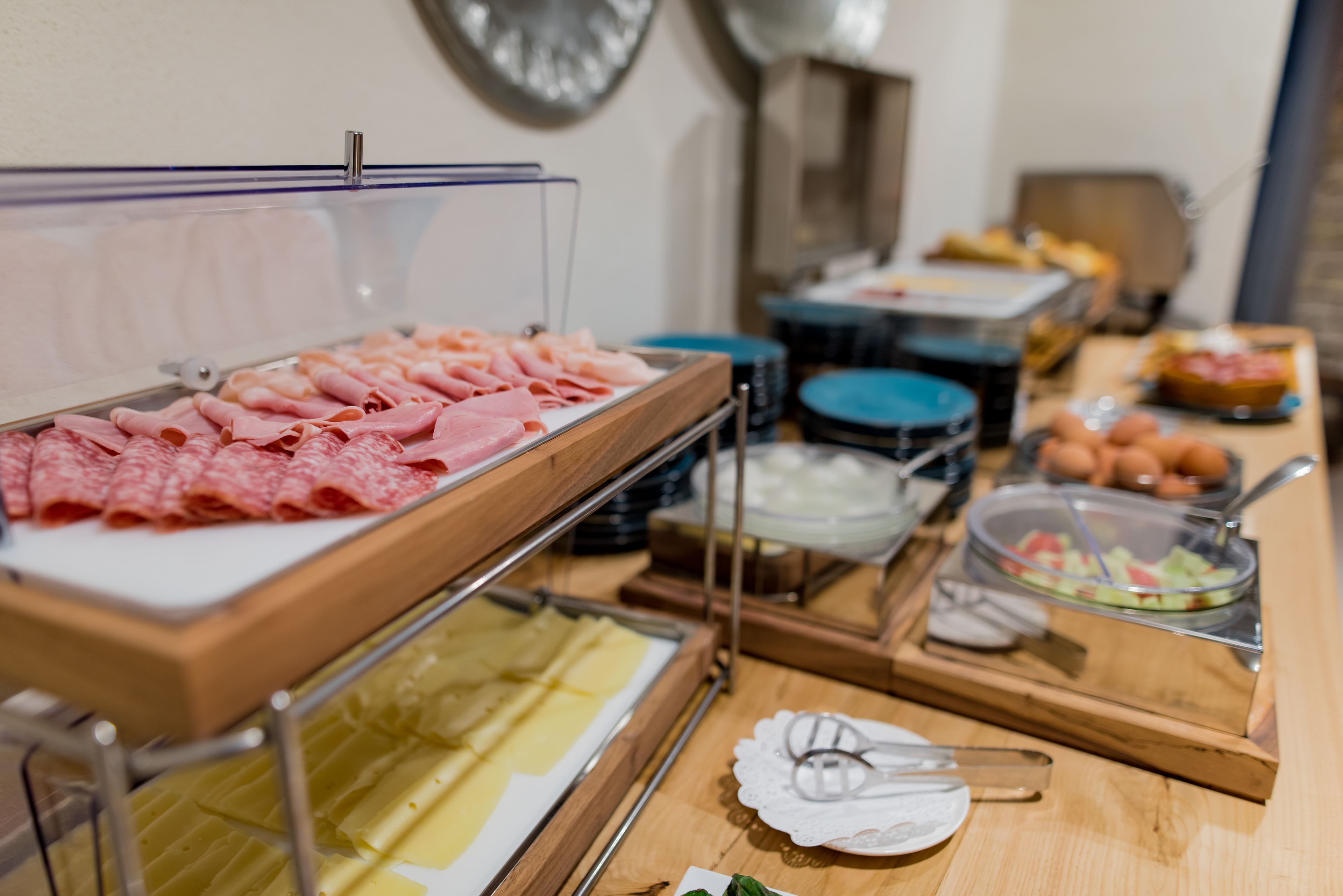 A buffet setup with various food items including sliced meats, cheeses, and a salad.