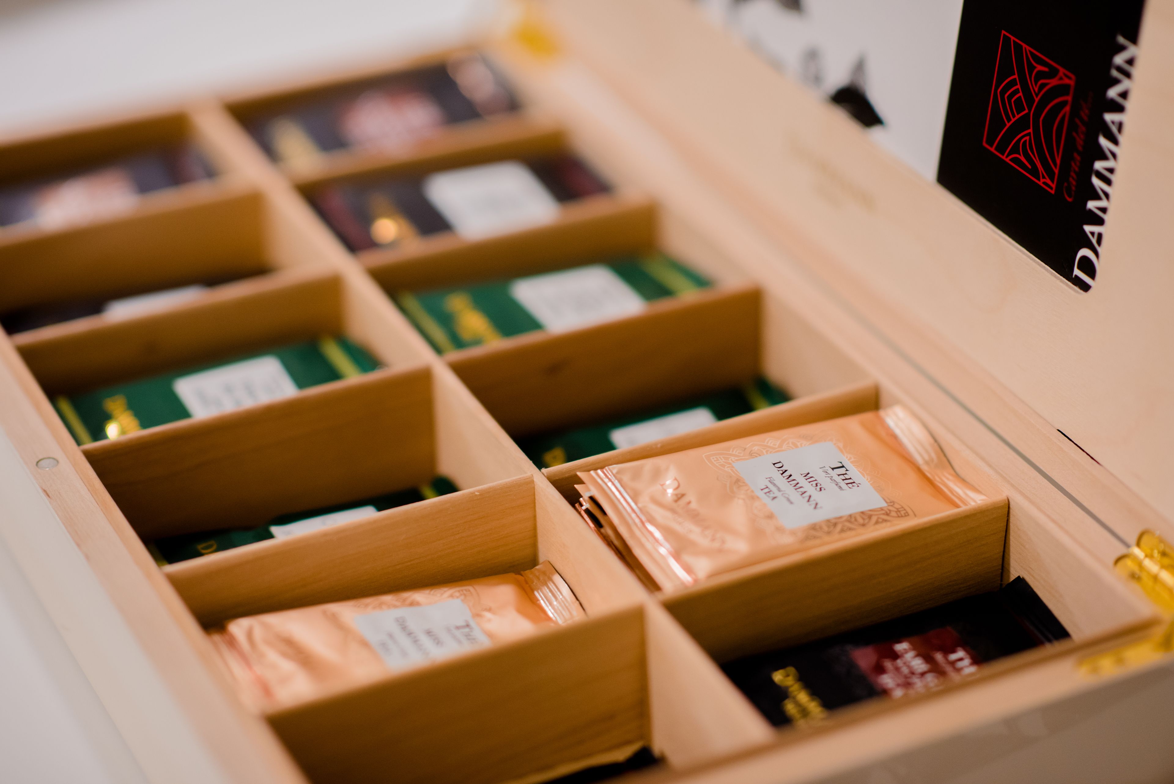 Una caja de madera con compartimentos que contiene diversos objetos, incluyendo una etiqueta de marca visible.