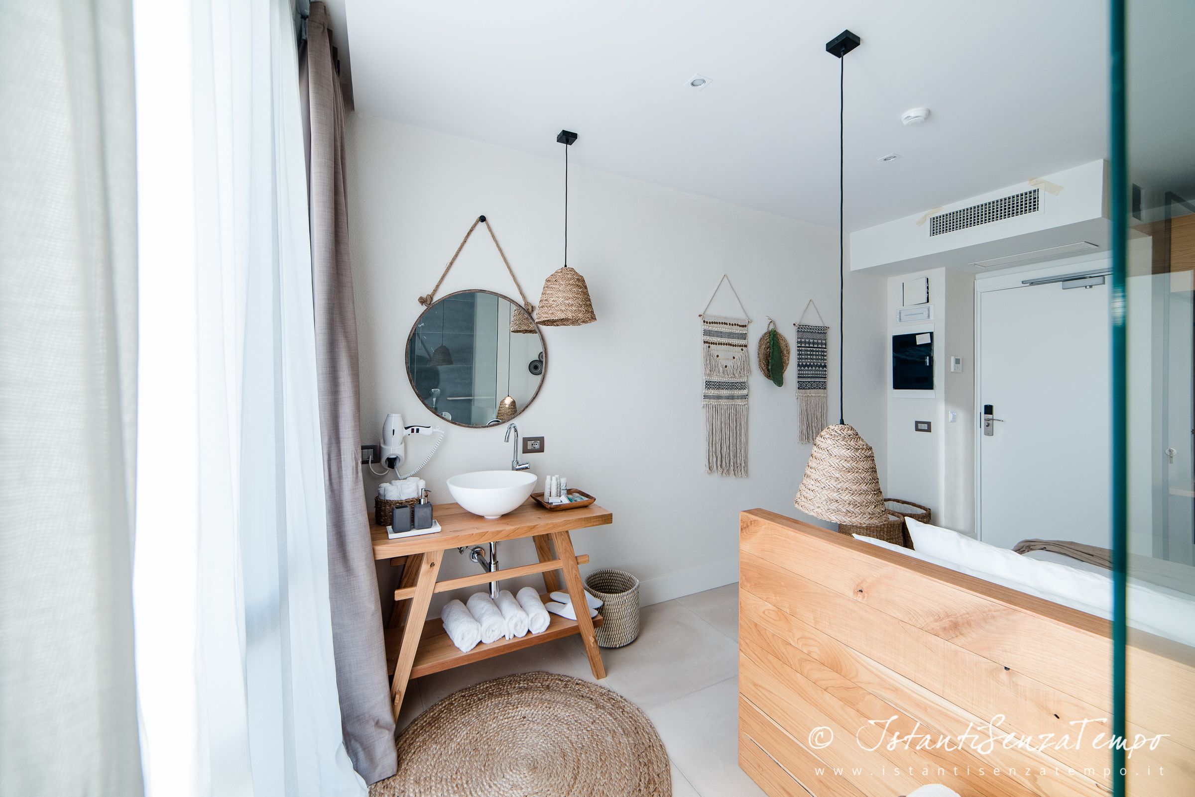 Une salle de bain moderne avec un meuble-lavabo en bois, un miroir rond et un luminaire suspendu.