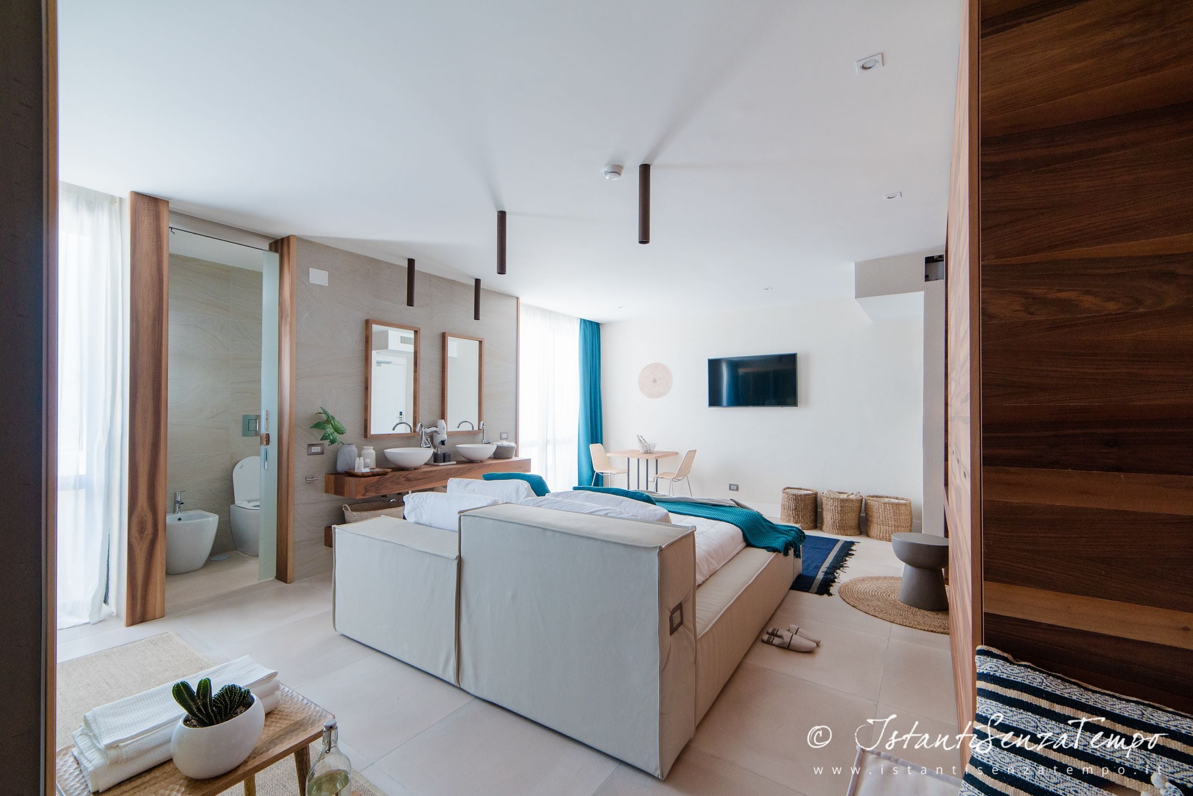 Ein modernes Schlafzimmer mit Bett, Nachttisch und Blick ins Badezimmer.
