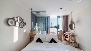 A modern bedroom with a large bed, a wooden bedside table, a mirror, and a view of the outdoors. - Cumeja - Beach Club & Hotel (Cellole)