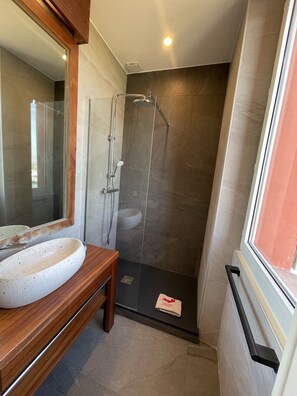 A modern bathroom with a glass-enclosed shower, a wooden vanity with a white speckled sink, and a large mirror. - L'oustaou de Porquerolles (Hyères)