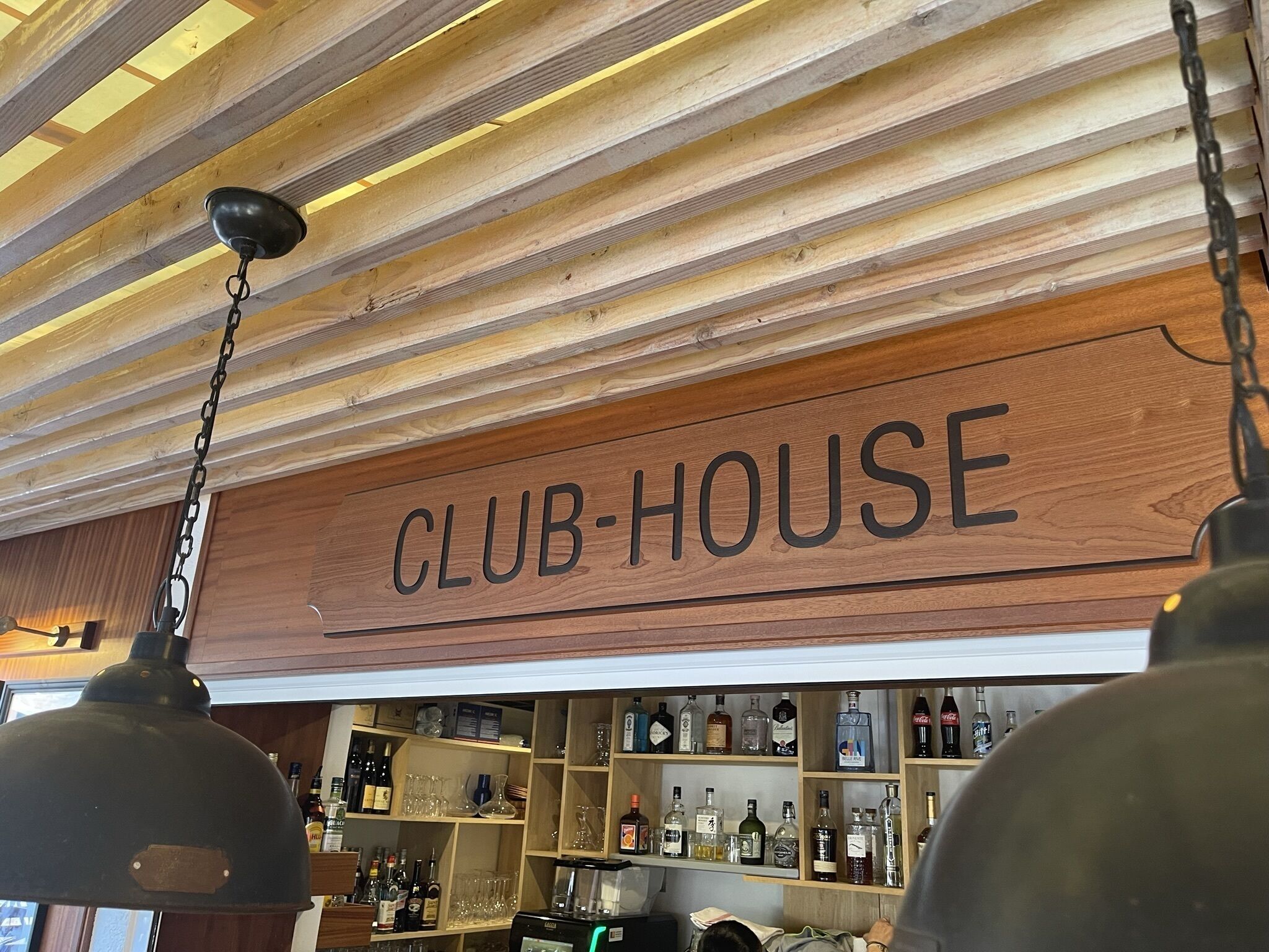 Un letrero de madera con la palabra 'CLUB-HOUSE' colgando del techo.